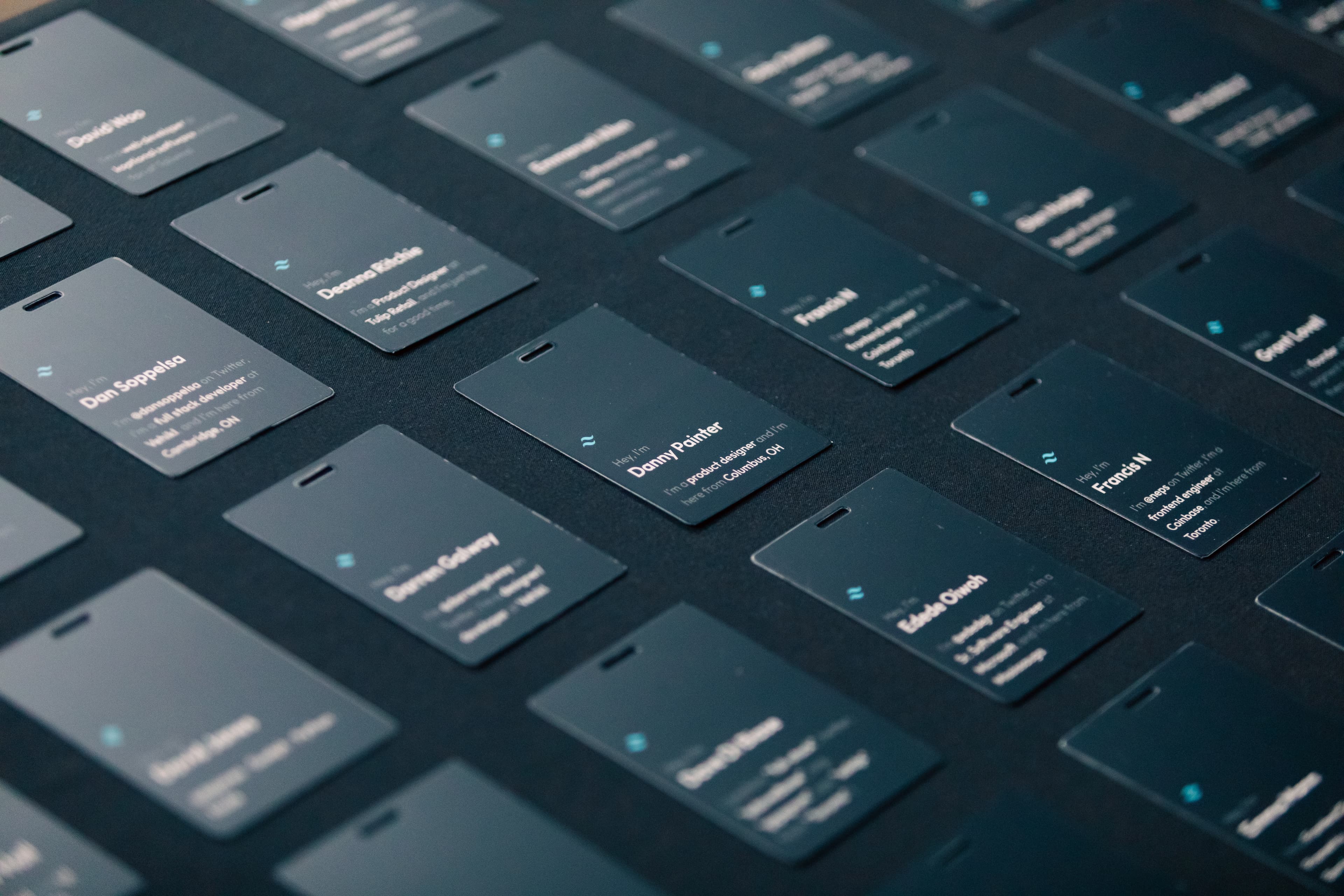 Insignias de asistentes dispuestas sobre una mesa cerca de la entrada del evento