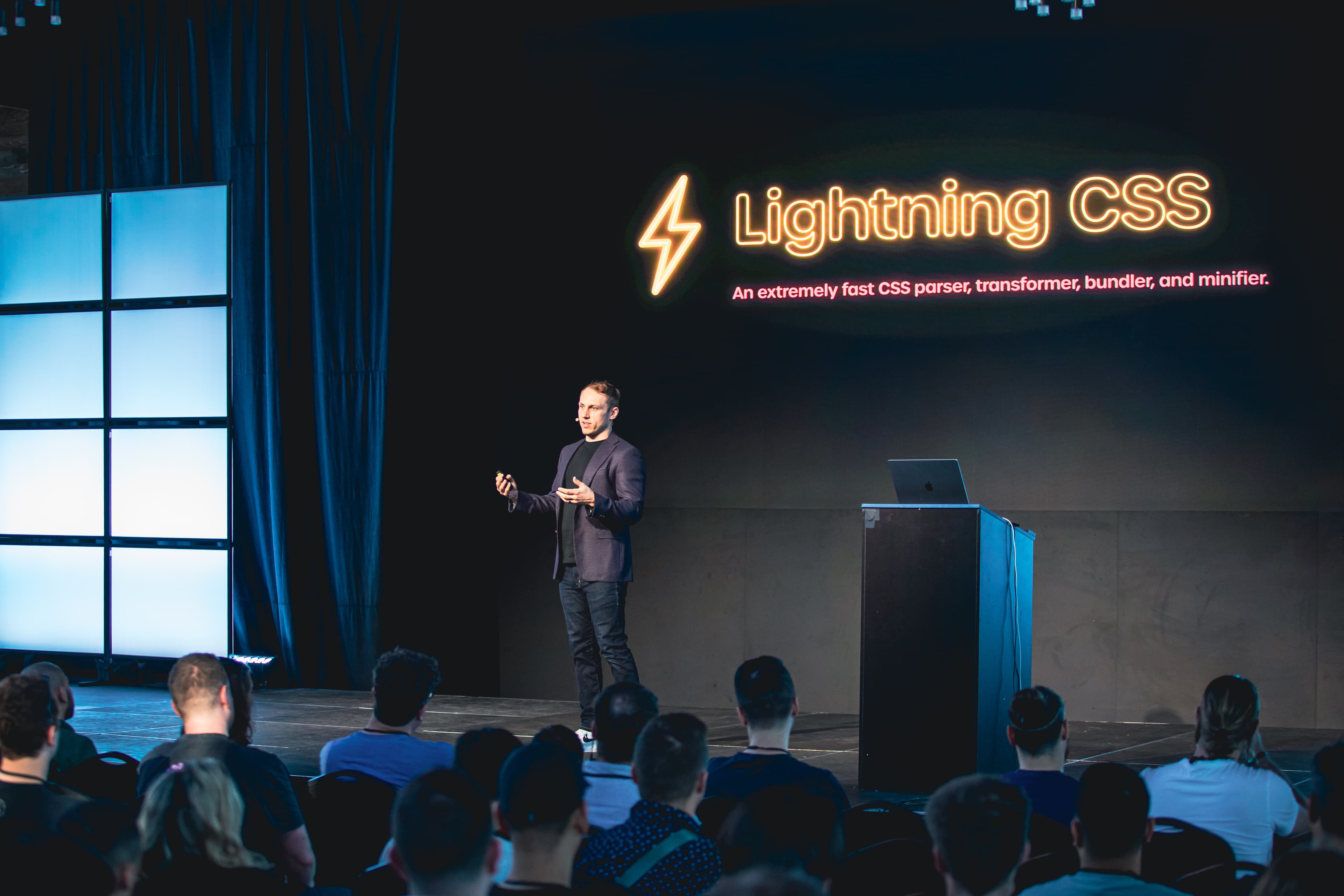 Adam Wathan en el escenario frente a una diapositiva que dice Lightning CSS